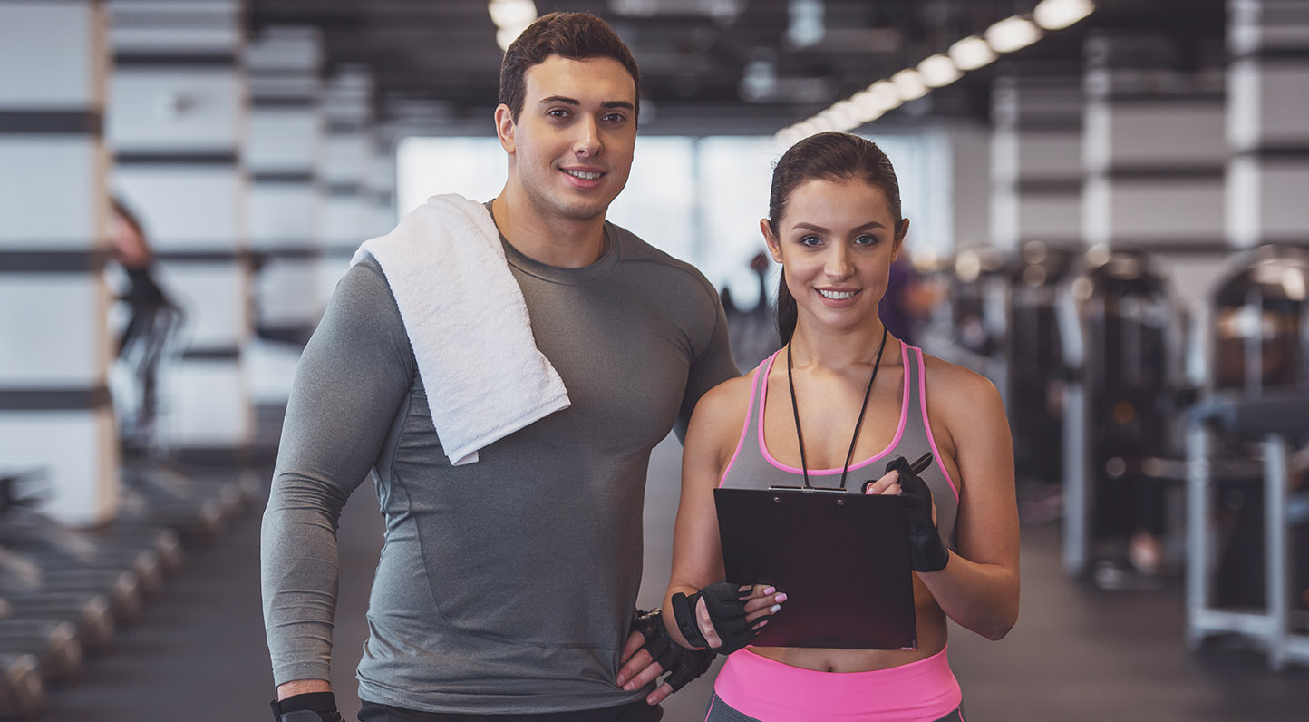 People in gym Attractive young muscular man and woman doing plank exercise while working out in gym